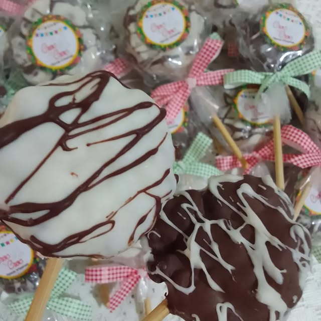 Pirulitos de chocolate branco e ao leite, com riscos de chocolate por cima.